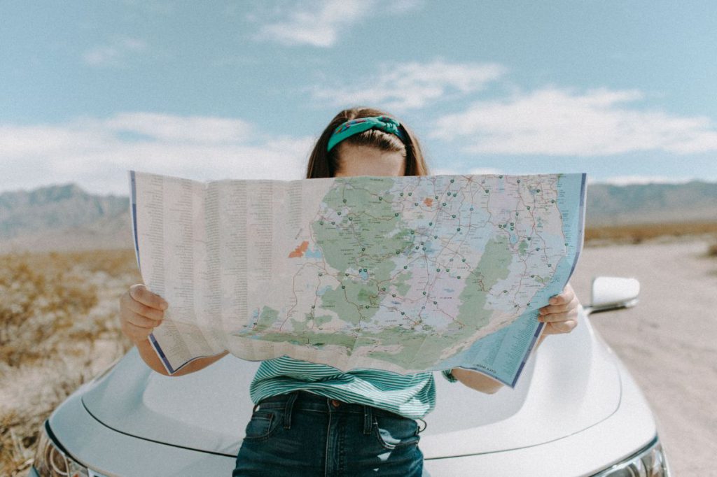 woman reading a map infront of a car