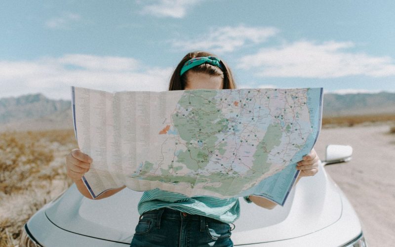 woman reading a map infront of a car